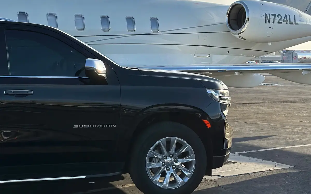 Black Suburban in front of a private jet on the tarmac for FBO and private aviation pickups